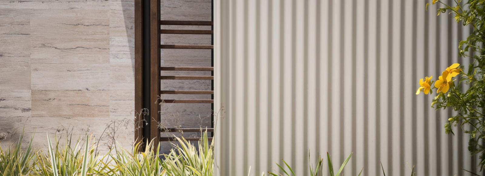 Close up image of fence which sits next to a sandstone wall.