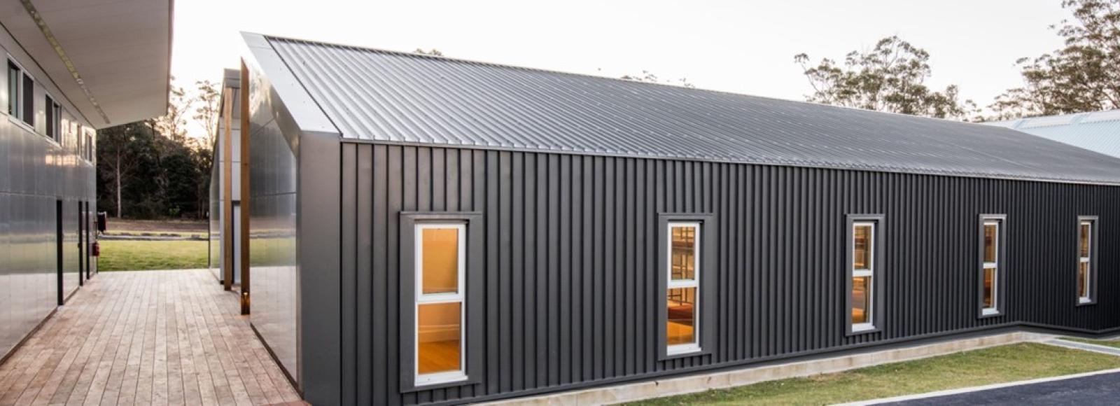 Modern building with Woodland Grey® COLORBOND® steel cladding, vertical panels, and warm-lit windows.