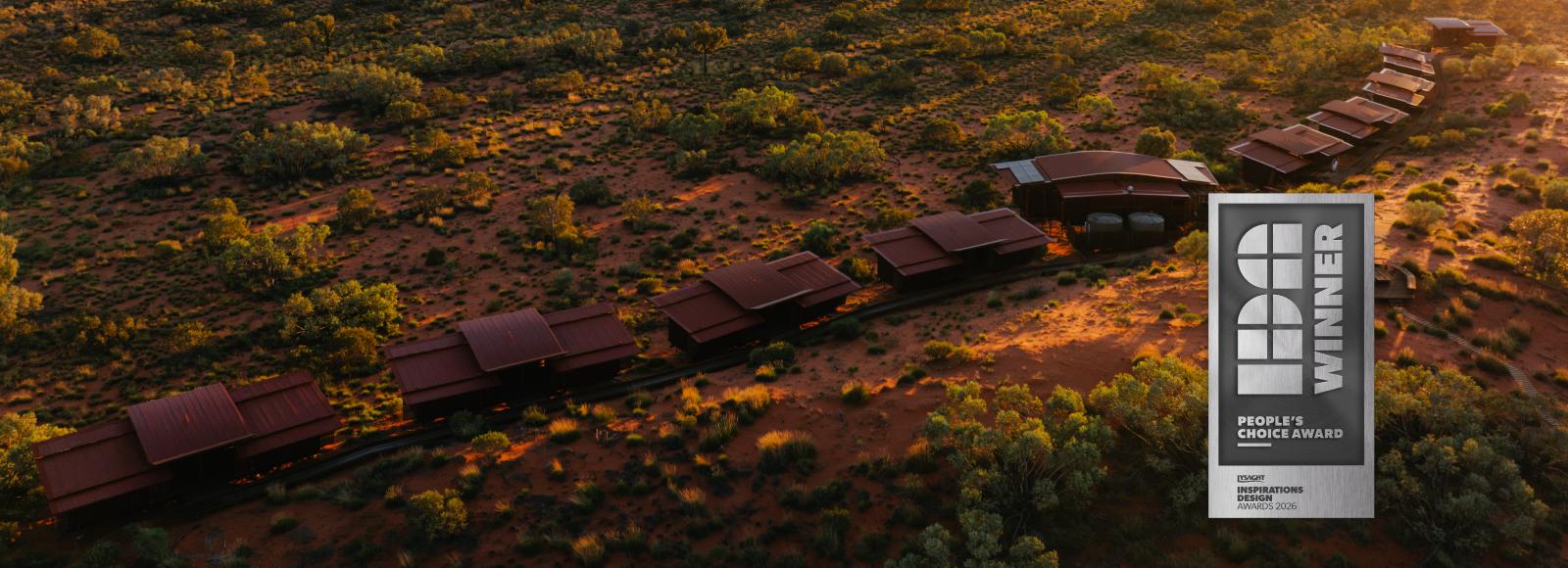 Aerial view of red-roofed eco-lodges across desert scrub at sunset, with People's Choice badge