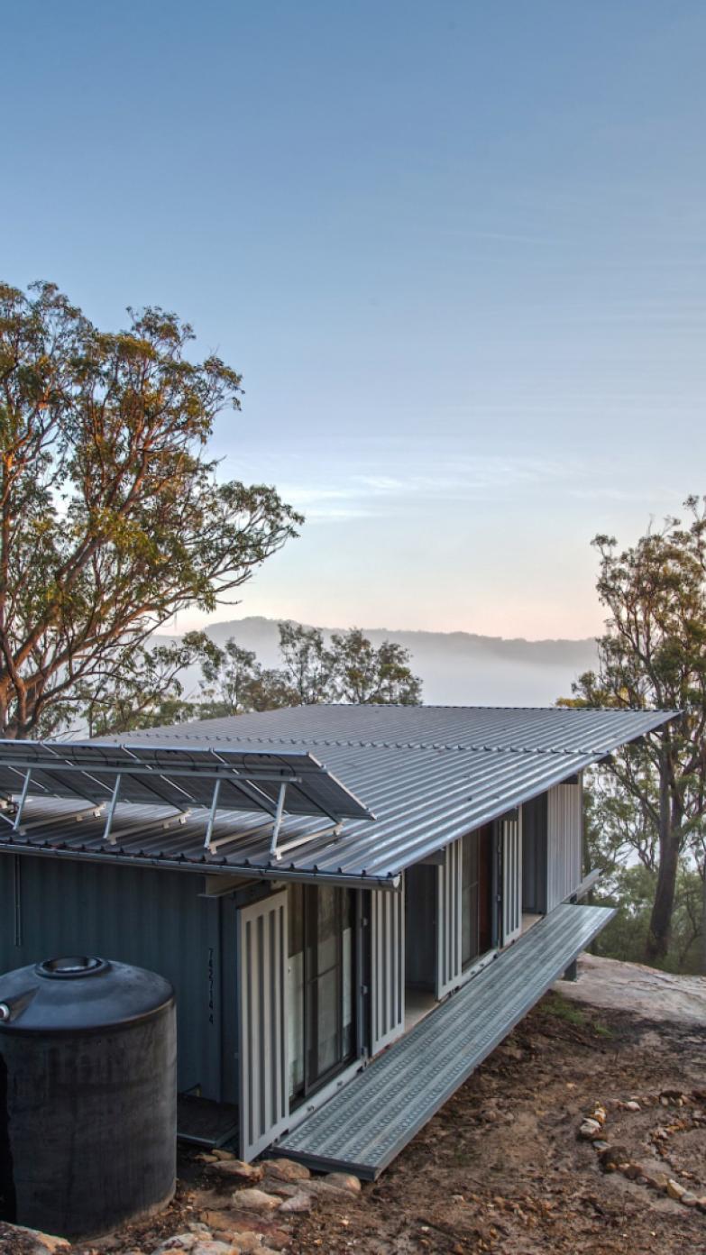 A photo of Peats Ridge, showing a building clad in Lysaght KLIP-LOK® overlooking a misty valley in the Aussie bush