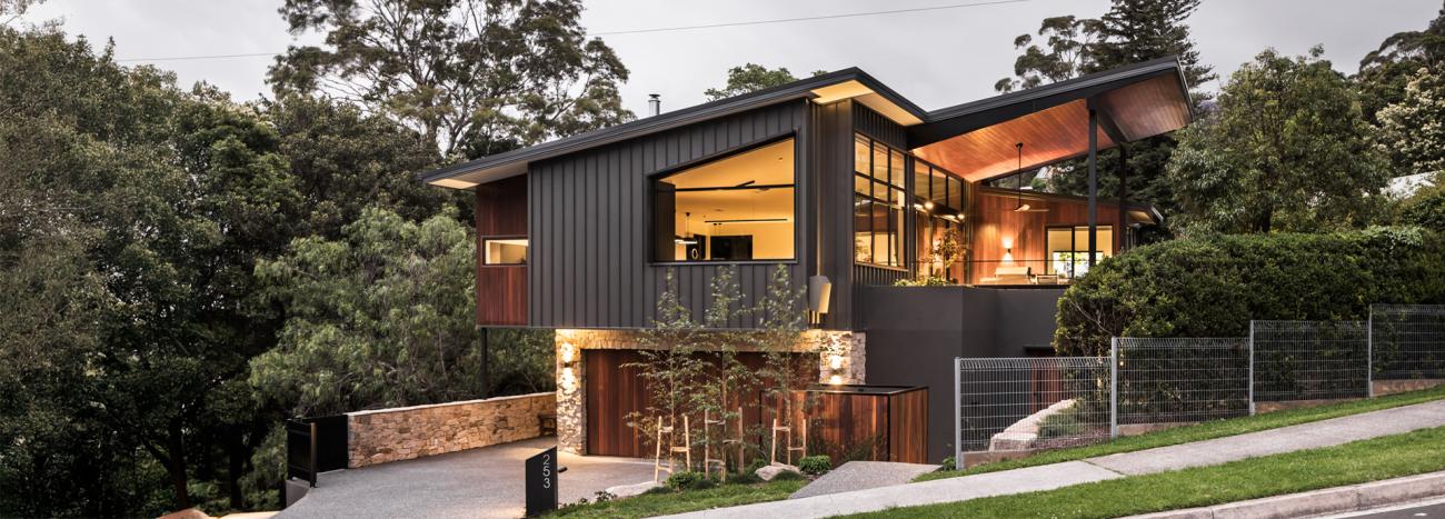 Elevated modern house with COLORBOND® Monument® steel wall cladding and a striking angular roofline