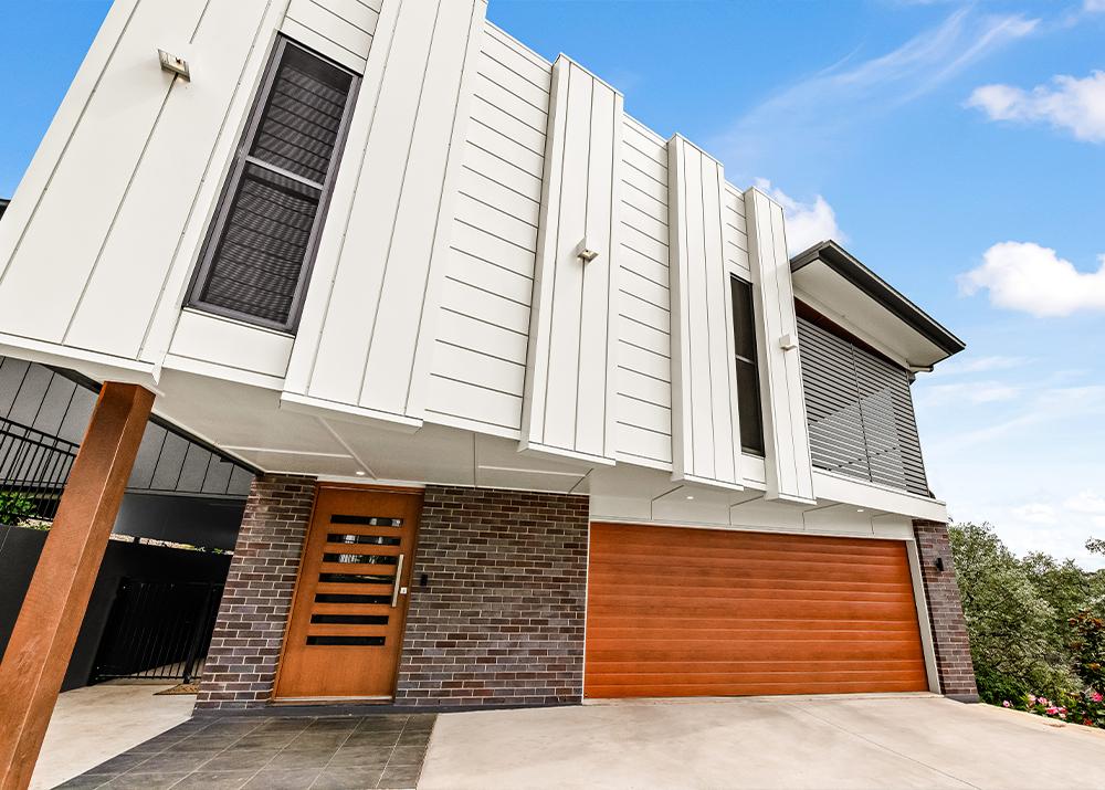 Modern urban home with white vertical Lysaght cladding and contrasting brickwork