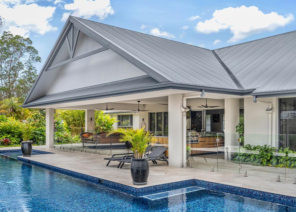 Modern home with a gabled roof in COLORBOND® steel Basalt® overlooking a luxurious pool area.