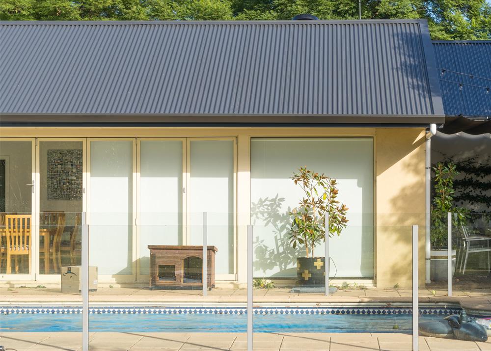 Poolside home with pitched roof clad in LYSAGHT® corrugated roof sheets made from COLORBOND® steel