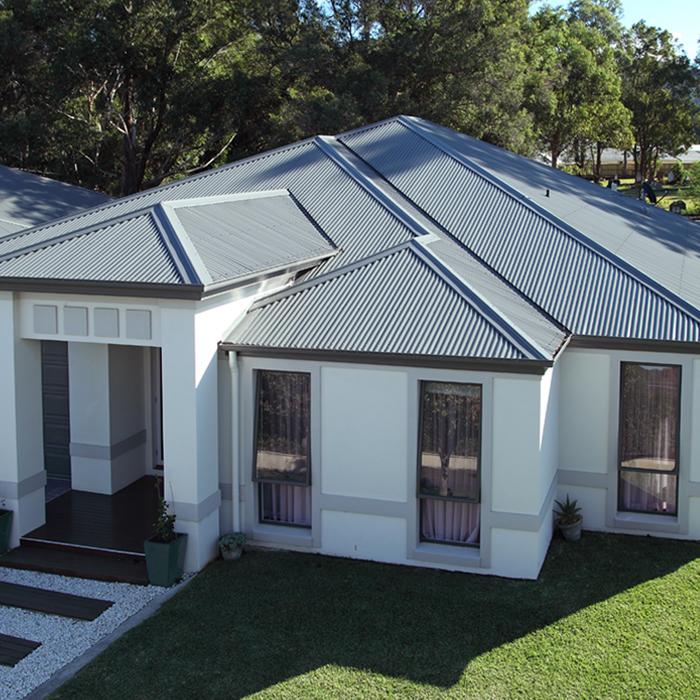 Light-coloured steel roof on a modern home, showing flashings supporting weatherproofing roof junctions.