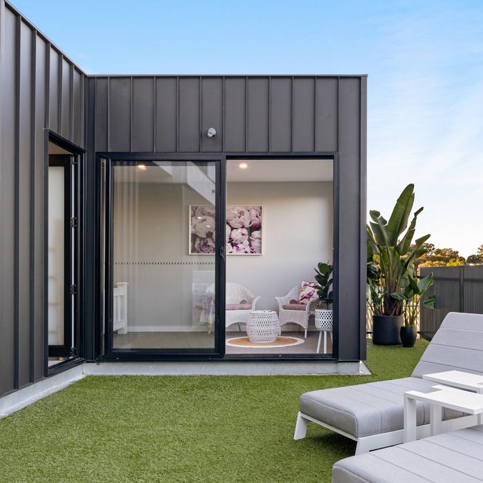 Outdoor living area framed by LYSAGHT ENSEAM® cladding, showcasing clean modern cladding lines.