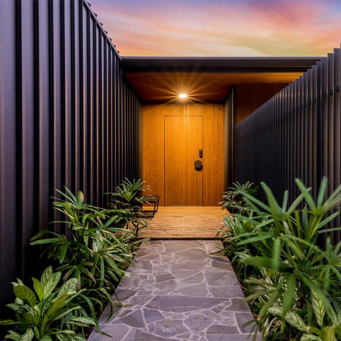 Vertical LYSAGHT ENSEAM® cladding shaping a modern exterior entryway with strong, linear facade design.