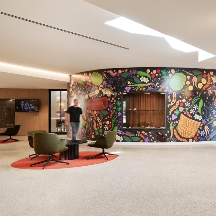 Close-up of ochre steel screening with circular openings beside ribbed wall cladding. Larnangurrak’s lounge with green chairs, a colourful mural and an angular skylight.