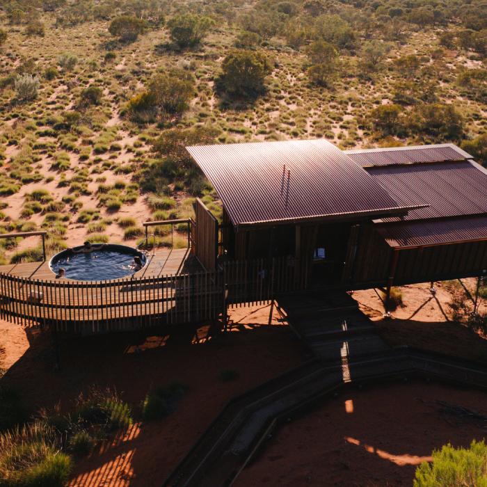 Aerial view of an eco-lodge with a round plunge pool on a deck in desert scrub