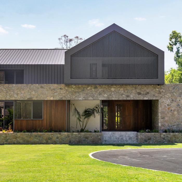 MacKenzie House's front gable screened with vertical battens above a natural stone base and timber entry.