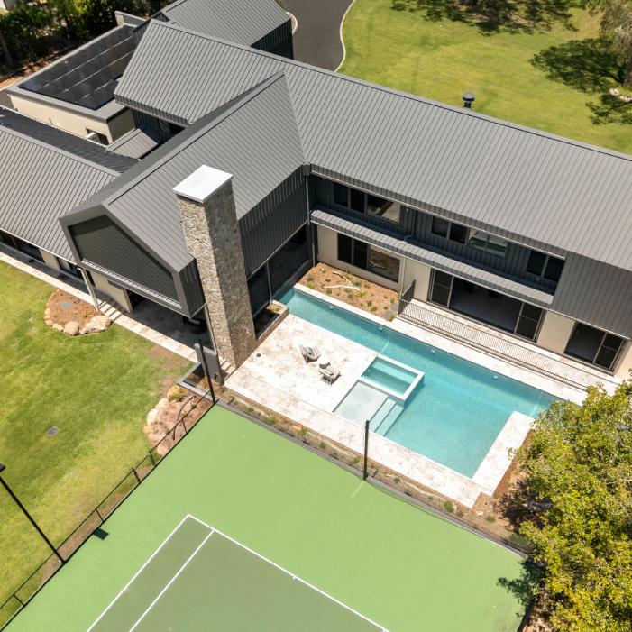 Aerial view of MacKenzie House’s steel roofs, pool, spa and tennis court.